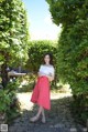 A woman in a white top and pink skirt posing for a picture.