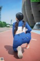 A woman in a blue and white outfit crouching on a track.