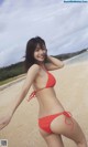 A woman in a red bikini standing on a beach.