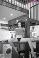 A woman sitting on top of a wooden table in a kitchen.