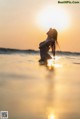 A woman standing in the ocean at sunset.