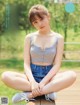 A young woman sitting on a wooden bench in a park.