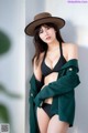 A woman in a black bikini and a green coat.