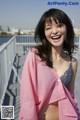 A woman in a pink shirt smiles at the camera.