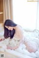 A woman in a white lingerie sitting in a bathtub covered in foam.