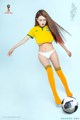 A woman in a yellow shirt and white panties kicking a soccer ball.