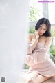 A woman in a pink dress sitting on a window sill.