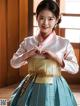 A woman in a blue and white hanbok is posing for a picture.