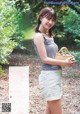 A woman holding a basket of blueberries in a forest.