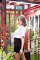 A woman in a white shirt and black skirt posing for a picture.