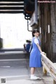 A woman in a blue dress standing on a bridge.