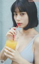 A woman holding a glass of orange juice with a straw.