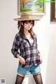 A woman wearing a straw hat and a plaid shirt.