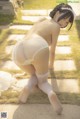 A woman in a white lingerie crouching down on the ground.