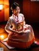 A woman in a traditional korean dress sitting on the floor.